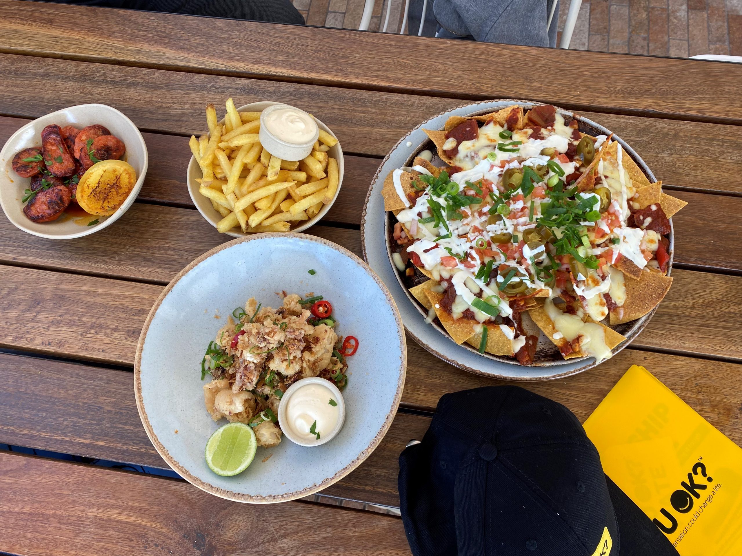 Four bowls of food containing fries, nachos, calamari and potatoes