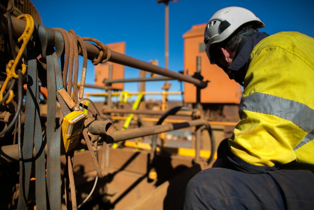 mining worker wearing a helmet looks down on worksite